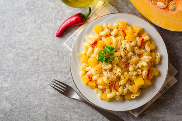 Pasta with pumpkin, chili and cheese in plate on stone background