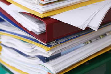 Pile of different file folders or ring binders full with office documents and paper work
