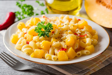 Pasta with pumpkin, chili and cheese in plate on stone background