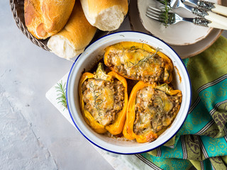 Bell peppers stuffed with barley and meat baked in enamel tin on gray