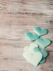 Fototapeta premium Green pastel hearts on textured wooden table. Valentine's day or baby birthday greeting card. toned