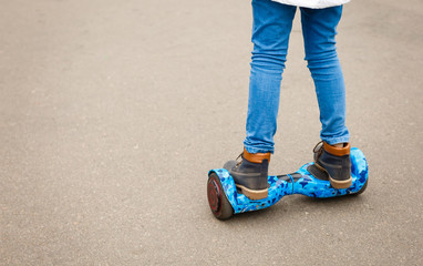 Feet of girl riding electric mini hover board scooter outdoors in park