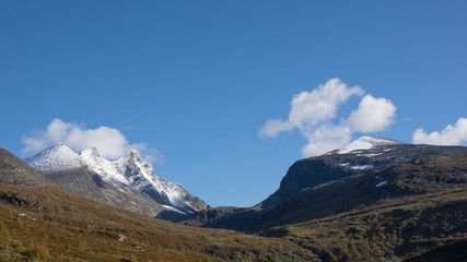 Mountain scenery with snow on the high peaks against blue sky background