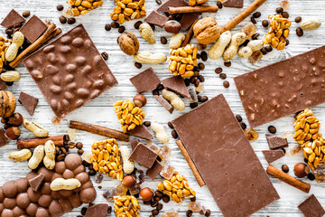 Cook homemade chocolate. Chocolate bars, nuts, sugar, coffee beans, cinnamon on grey wooden background top view
