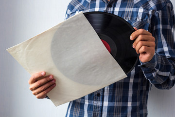 man holds white blank vinyl cover and vinyl record in hands