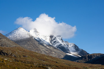 Mountain scenery with snow on the high peaks against blue sky background