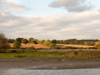 Fototapeta na wymiar farm fields across the river in autumn sunset light