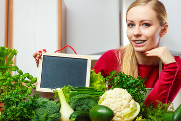 Woman having green vegetables holding board