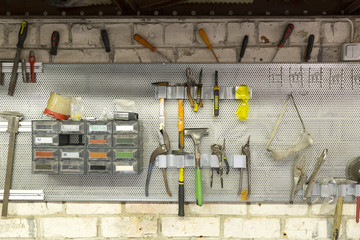 Old tools hanging on wall in metalwork workshop , Tool shelf against a wall