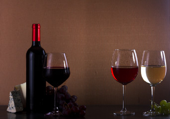 Wine concept - bottle and glasses with red, pink and white wine on table, copy space in background