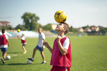 Boy Balancing a Football on His Head