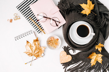 Workspace with golden maple leaves, notebook, coffee cup wrapped in scarf,  glasses. Stylish office...