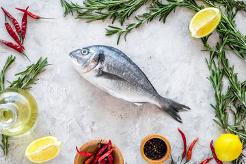 Mideterranean cuisine. Dorado with spices rosemary, pepper, chili, lemon. Grey background top view
