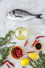 Mideterranean cuisine. Dorado with spices rosemary, pepper, chili, lemon. Grey background top view