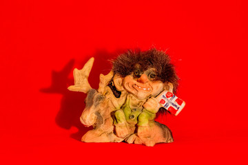 Funny shaggy troll toy from Norway on a red background
