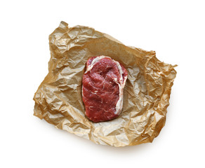 Raw beef steak in craft paper isolated on white