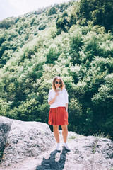 Naklejka premium Young woman on the rock in nature with flowers in her hands