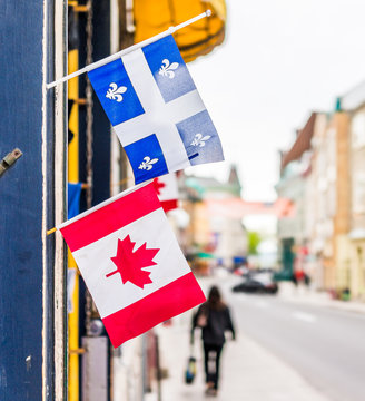 Closeup of two small Canadian and Quebec flags hanging on restaurant on Saint Louis street in old town road