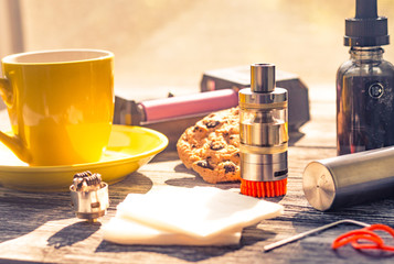 Still life with electronic cigarette with botle and coffe on the wooden background