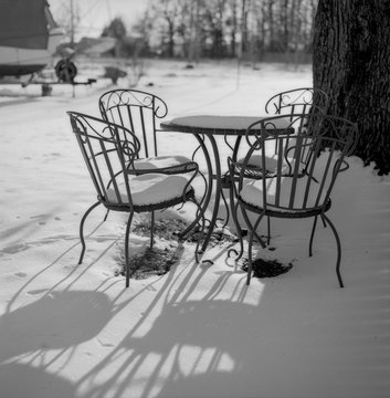 Snow-covered table and chairs at sunset