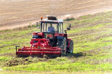 Obraz premium Red tractor in the field. Agricultural farm work. Agriculture in the Czech Republic.