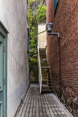 Lower old town street narrow alley with cobblestone and private entrance with sign, lantern and stairs to brick apartment