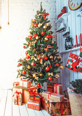 Attired Christmas tree set with presents and accessories at wooden and brick wall background in studio. Vertical orientation.