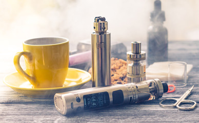 Still life with electronic cigarette with botle and coffe on the wooden background