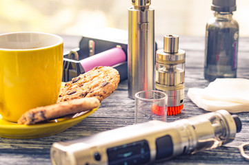 Still life with electronic cigarette with botle and coffe on the wooden background
