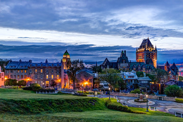 Fototapeta premium Pejzaż miejski lub panorama Chateau Frontenac, parku i ulic starego miasta podczas zachodu słońca z oświetlonym zamkiem i budynkami ulicznymi Saint Denis