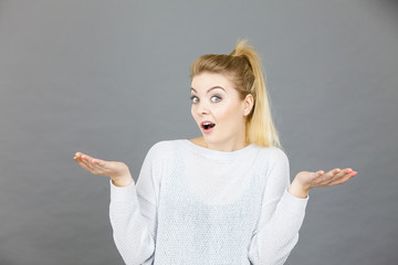 Confused young blonde woman gesturing with hands