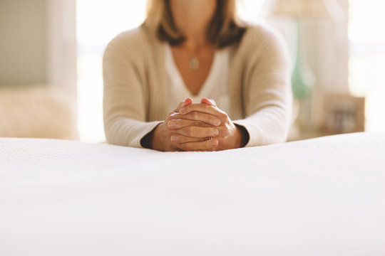 woman praying next to a bed