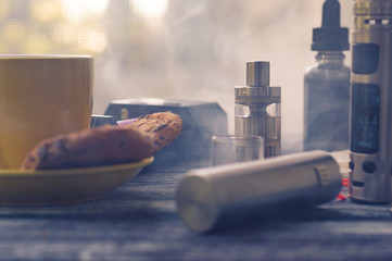 Still life with electronic cigarette with botle and coffe on the wooden background