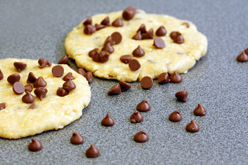 cooking snack: chocolate chip cookies on cutting table ready to be baked, grey background and copy space