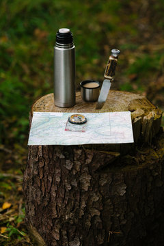 Map and a compass with coffee and a knife.