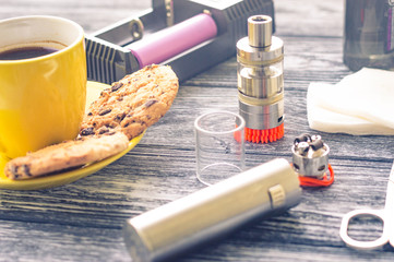Still life with electronic cigarette with botle and coffe on the wooden background