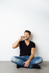 Fototapeta premium mann sitzt auf dem fußboden und telefoniert