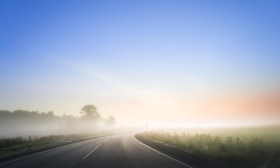 Nice winding road caught in the fog in winter time. Morning with red sunrise