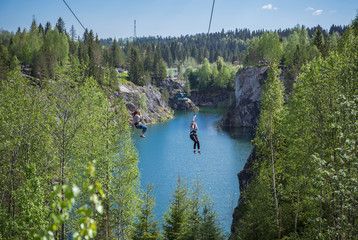 Tourist gliding on the zipline trip in the canyon Marble quarry in Ruskeala Park
