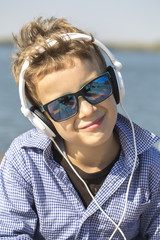 Portrait of a cute little boy with sunglasses, while listening to music