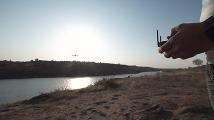 Crop shot of man holding remote controller and using quadcopter on natural background.