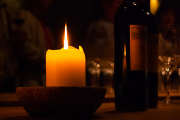 Burning candle on the table with a bottle of wine