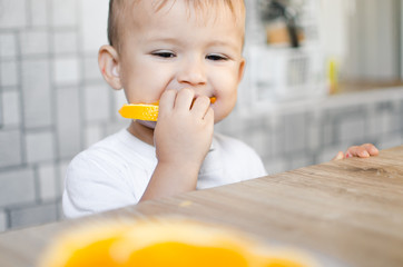 The child in the kitchen eating an orange