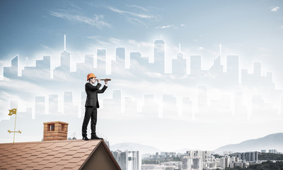 Engineer man standing on roof and looking in spyglass. Mixed med