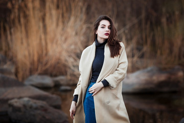 Portrait of a Stylish Pretty Young Woman in Autumn Fashion Coat walking outdoors.