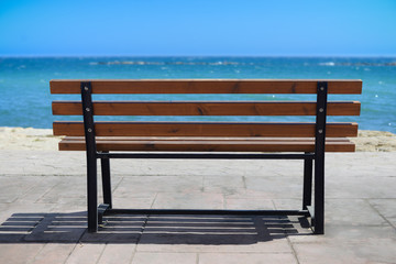 Fototapeta na wymiar Empty wooden rest bench at sea shore