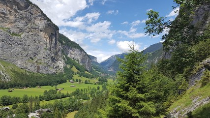 Fototapeta na wymiar Stunning Lauterbrunnen valley in the Jungfrau region in Switzerland. Lush green valley below with towering cliffs above.