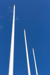 Three white flagpole, blue sky on background