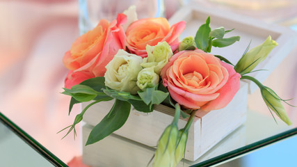white wooden box with fresh flowers stands on a mirrored table