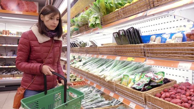Woman in supermarket selects fruit and vegetables.